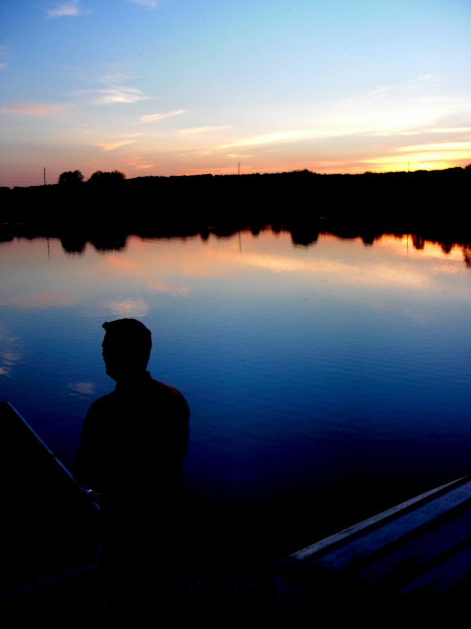 Free Image of Man Standing Next to Boat on Lake 
