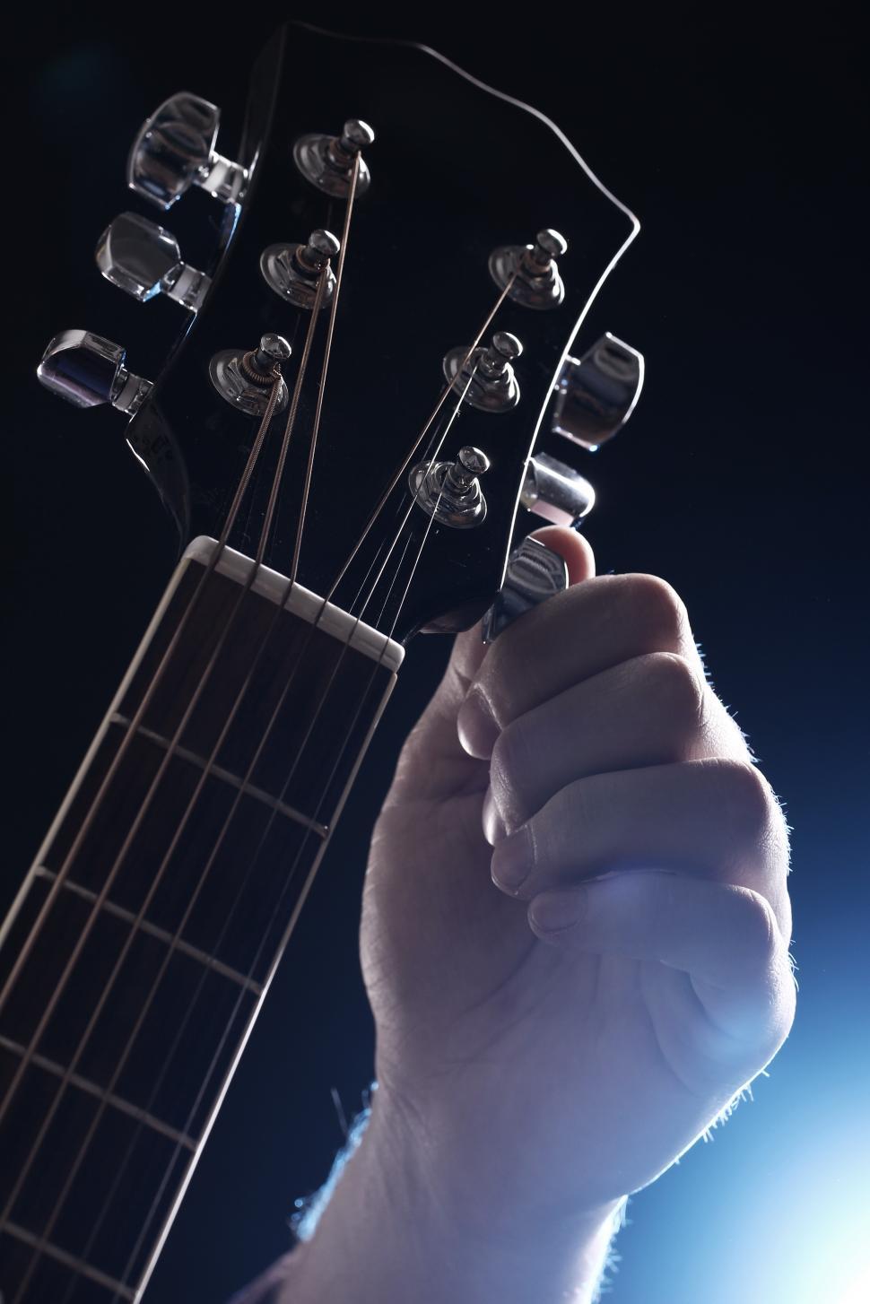 Free Image of Musician tuning a guitar under lights 
