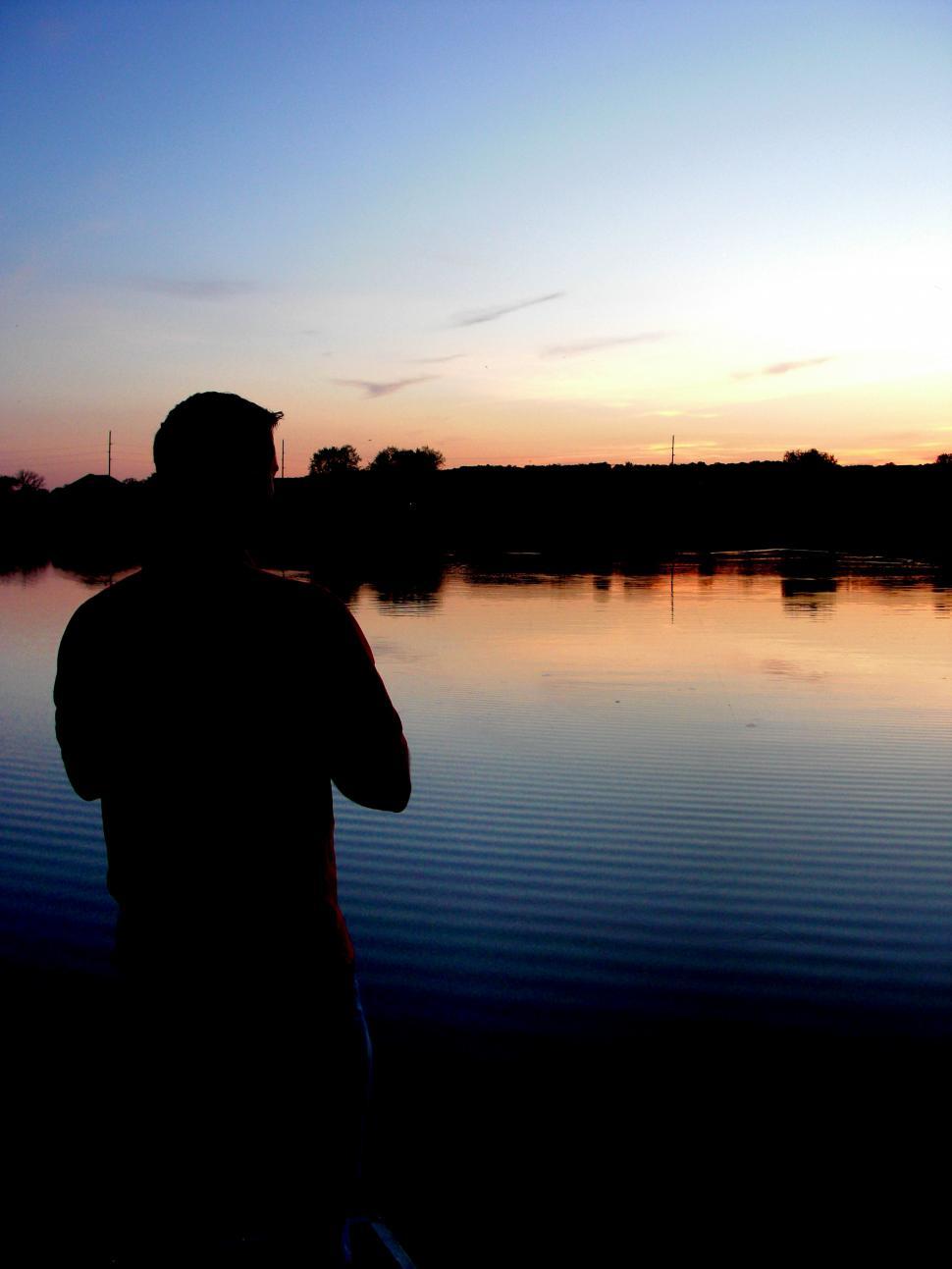 Free Image of Man Standing in Front of Body of Water 
