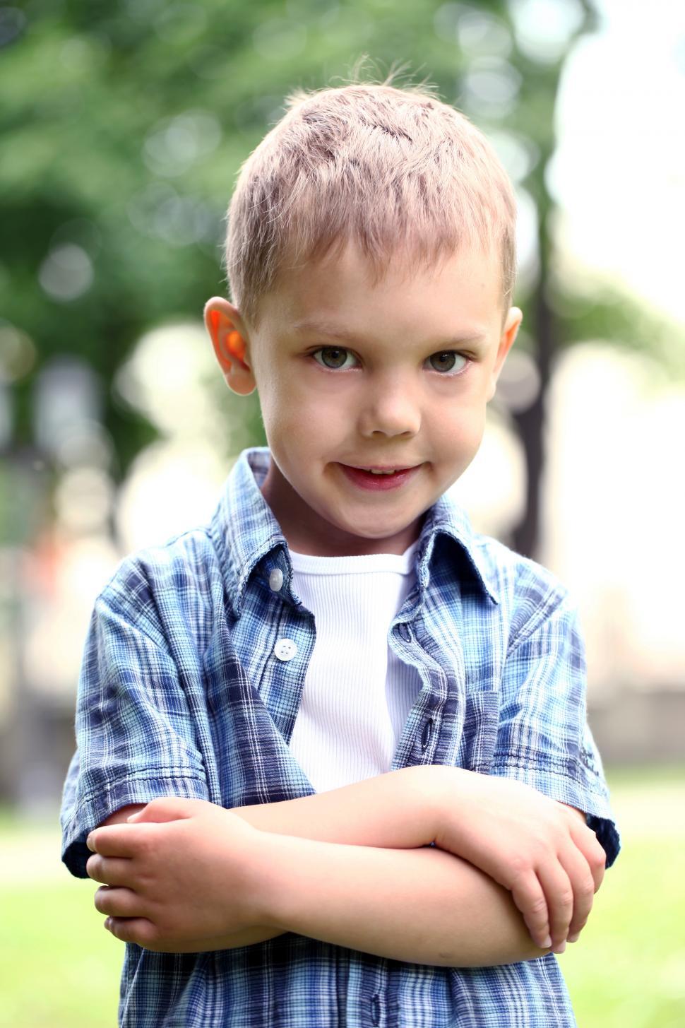 Free Image of Portrait of little boy with arms crossed standing in the park 