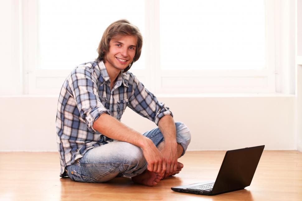 Free Image of Happy guy relaxing at home, sitting on the floor with laptop 