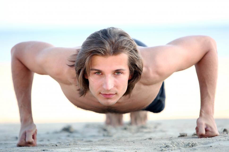 Free Image of Handsome man doing push ups on the beach 