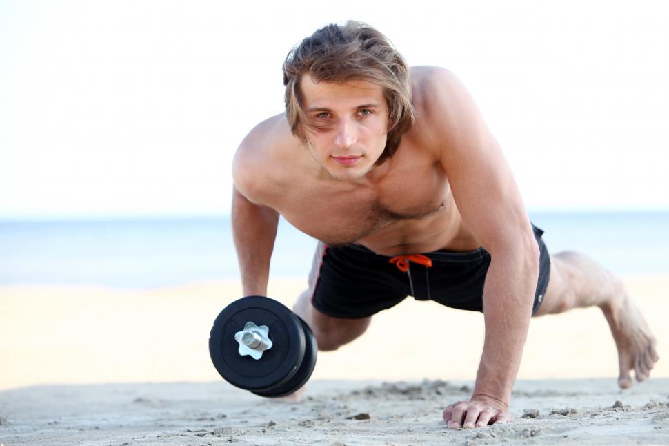 Free Image of Handsome man doing weight and fitness exercises on the beach 