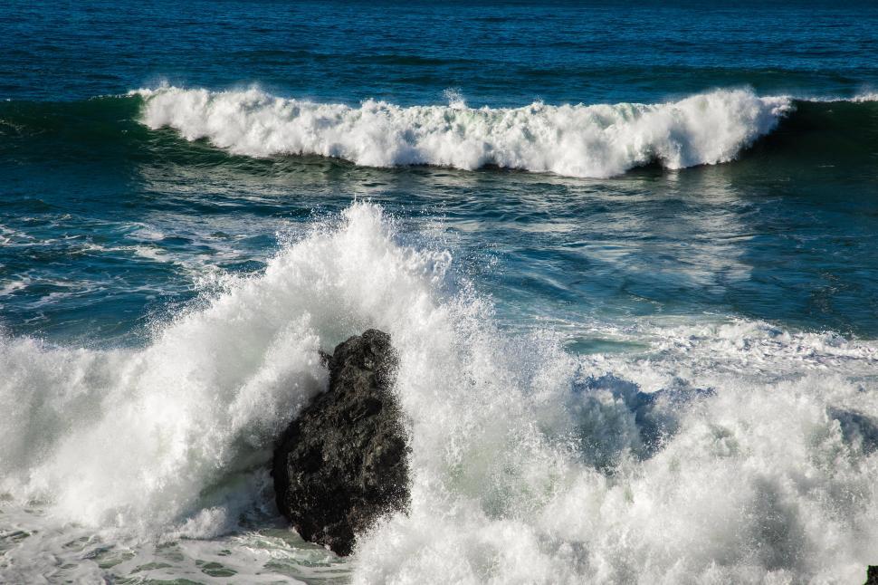 Free Image of Waves crest and crash over a rock 