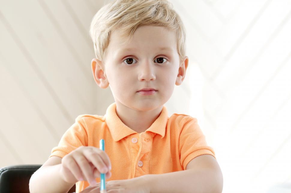 Free Image of Cute little boy with a pencil, sitting, looking at the camera 