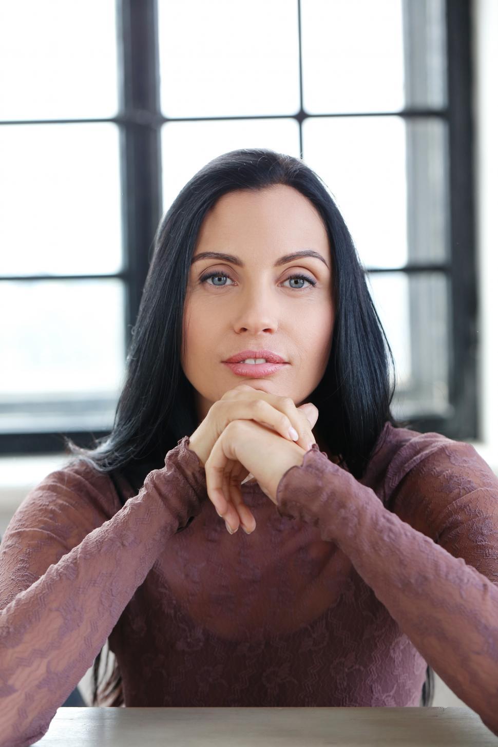 Free Image of Woman with hands folded together, looking at camera 