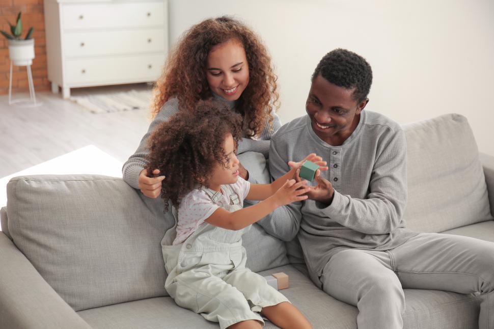 Free Image of Young smiling mother and father playing with girl child at home 