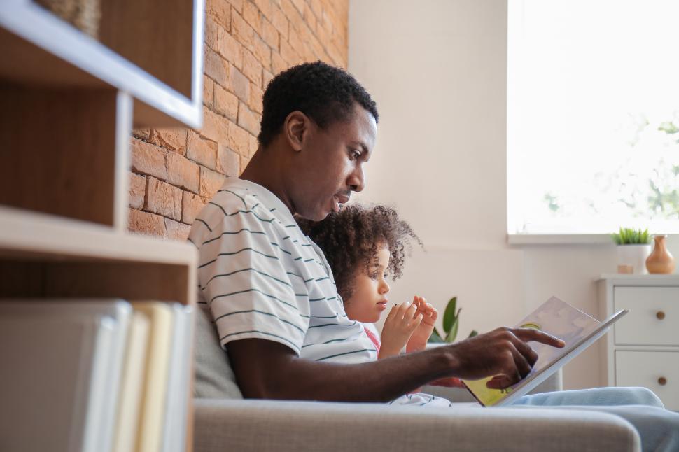 Free Image of Young man with little girl reading book at home 
