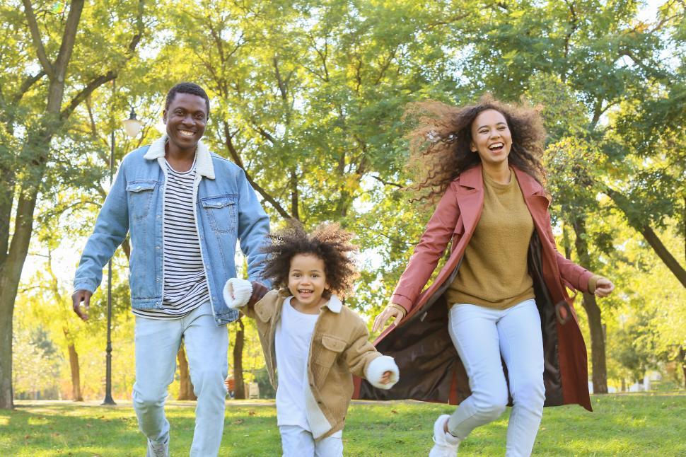 Free Image of Young smiling parents with their daughter walking in the park 