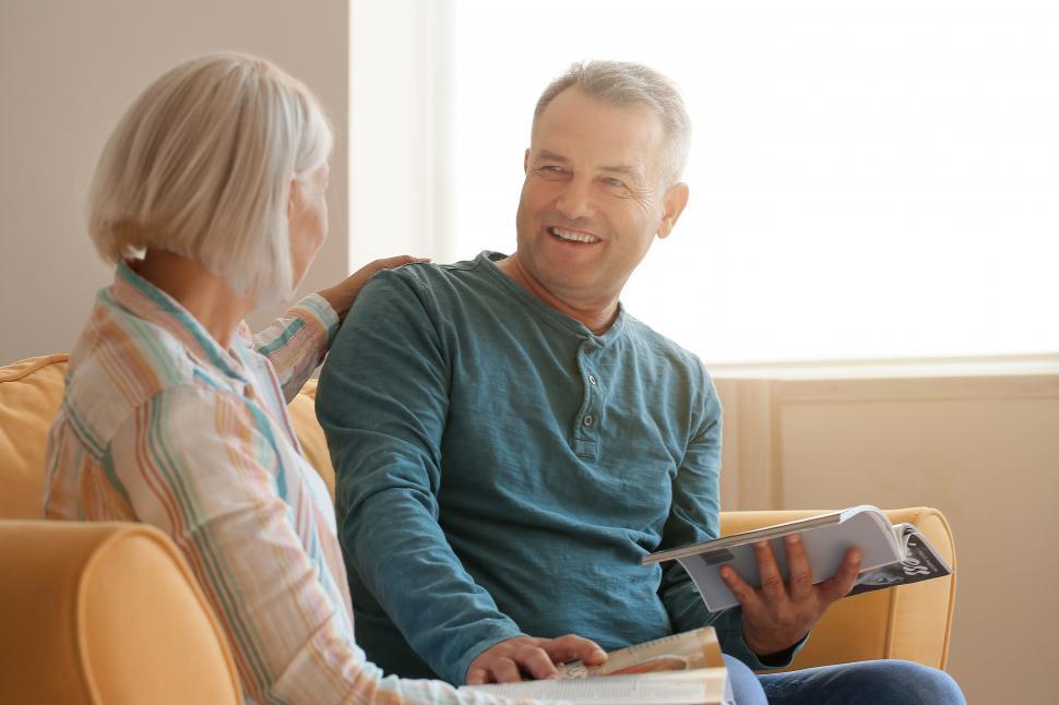 Free Image of Happy Couple smiling and reading magazine at home 