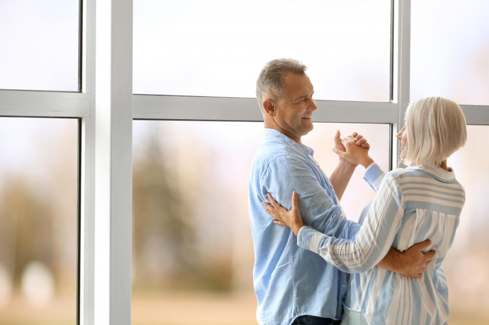Free Image of Happy couple dancing together near glass window 
