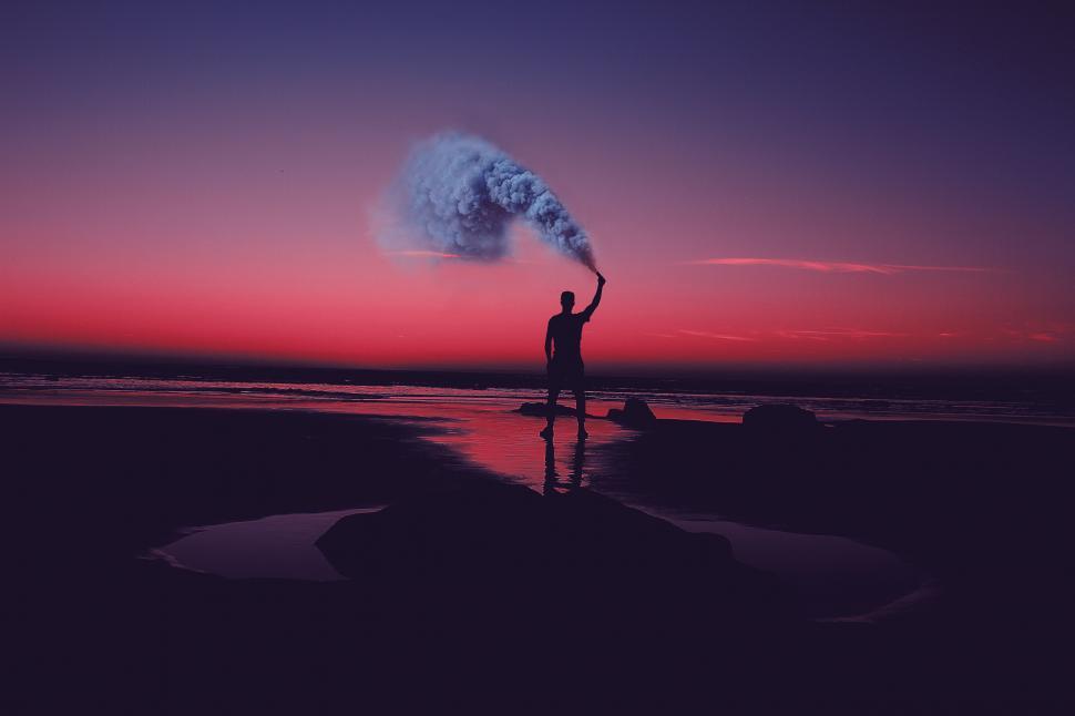 Free Image of Man at the beach with smoke flare during sunset 