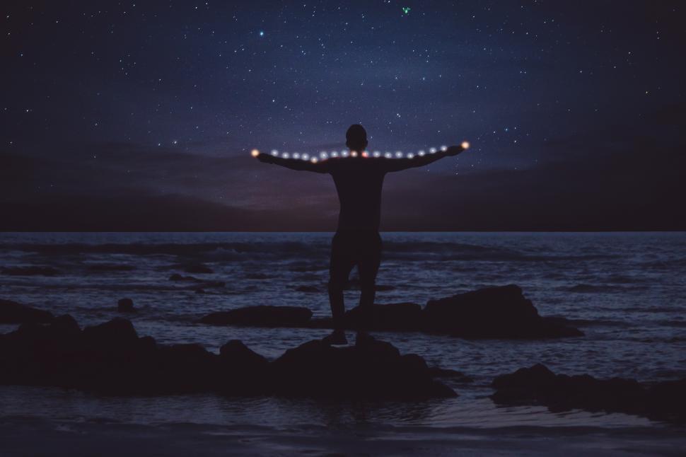 Free Image of Man with open arms at the beach with night sky 
