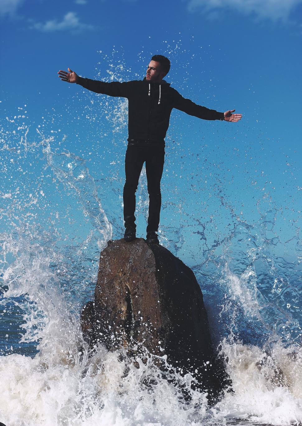 Free Image of Man on rock with splashing water 