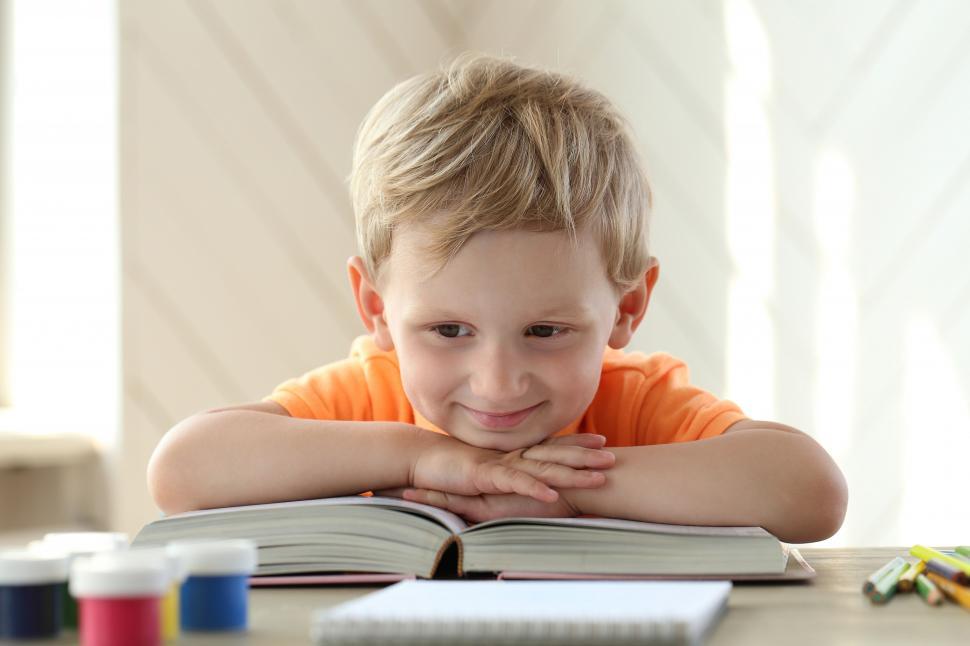 Free Image of Little boy reading a book at the table 