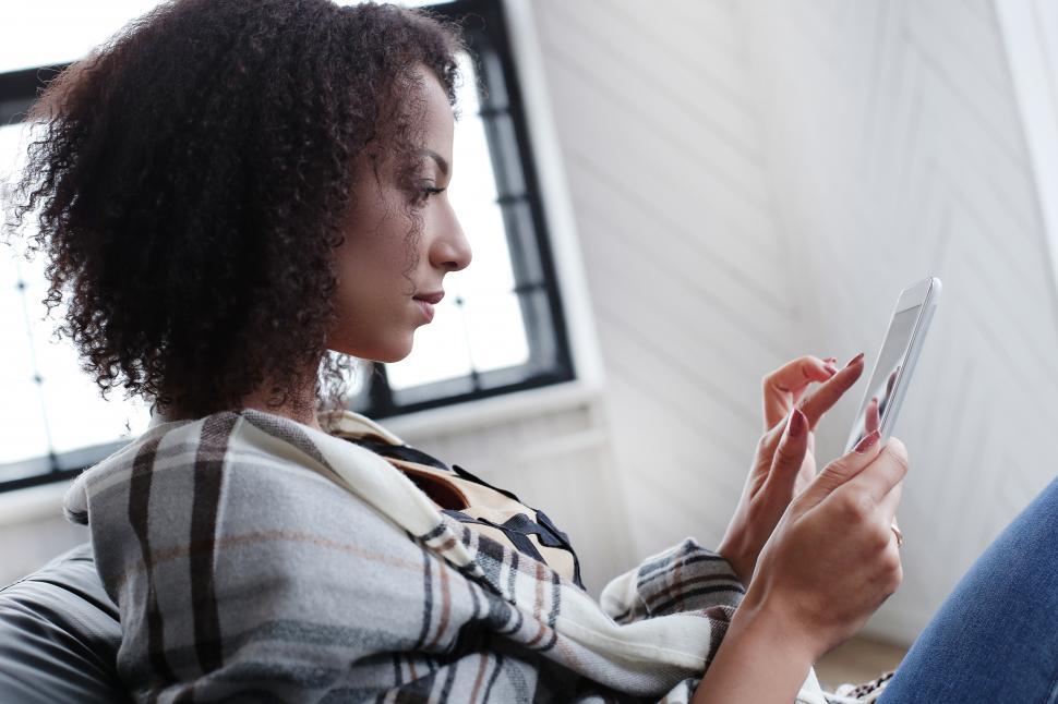 Free Image of Woman using a tablet device while on the couch 