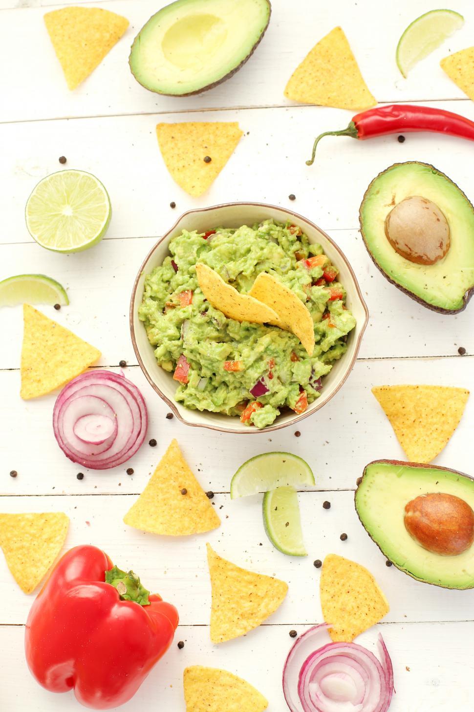 Free Image of Guacamole dip surrounded by chips and vegetables 