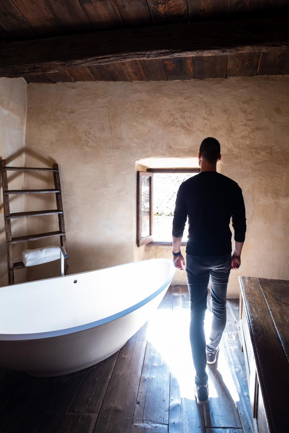 Free Image of Rear view of man standing and walking in the vintage hotel bathroom 