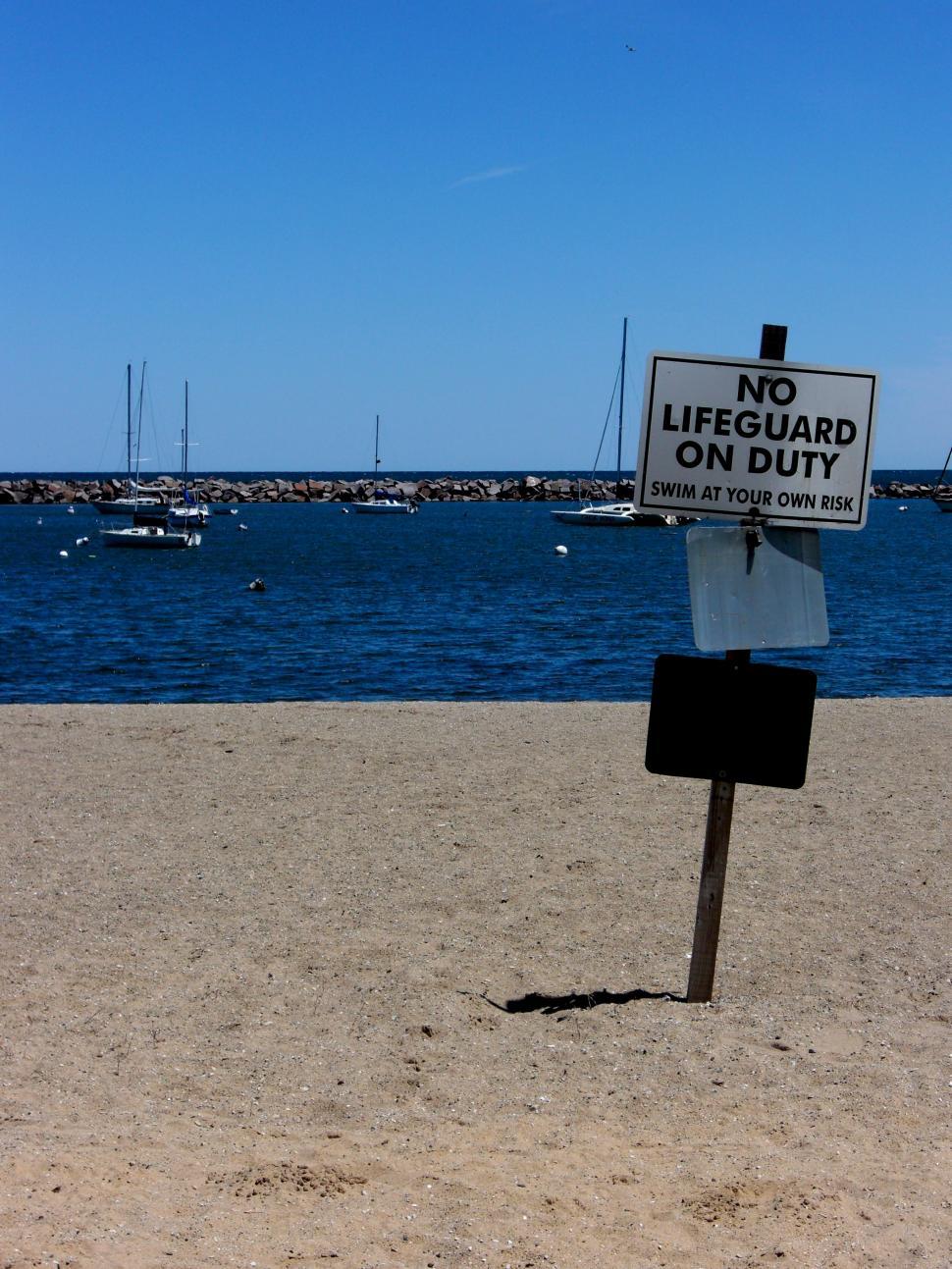 Free Image of Sign Positioned on Sandy Beach Near Water 