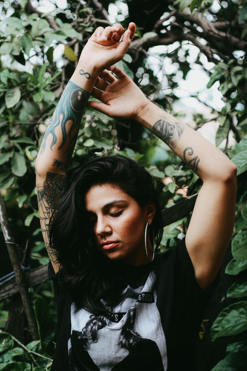 Free Image of Urban woman standing in the park with tattoos on hands 