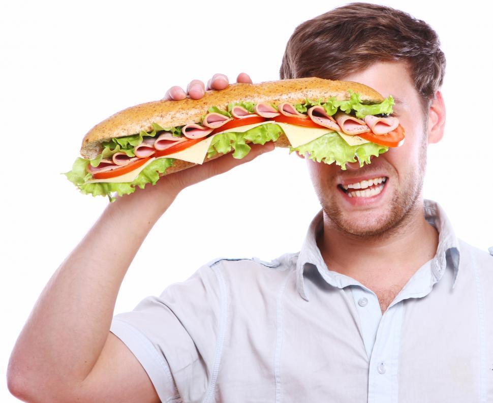 Free Image of Young man obscured by a big submarine sandwich 