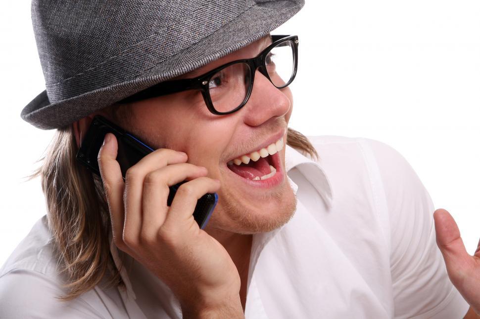 Free Image of Young guy in a hat taking excited on the phone 