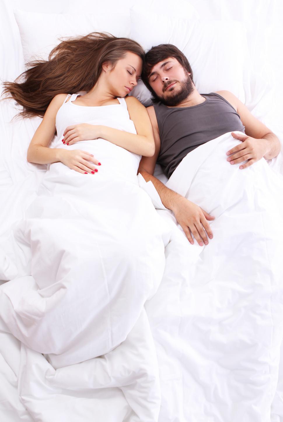 Free Image of Young couple sleep in bed, covered by white blankets 