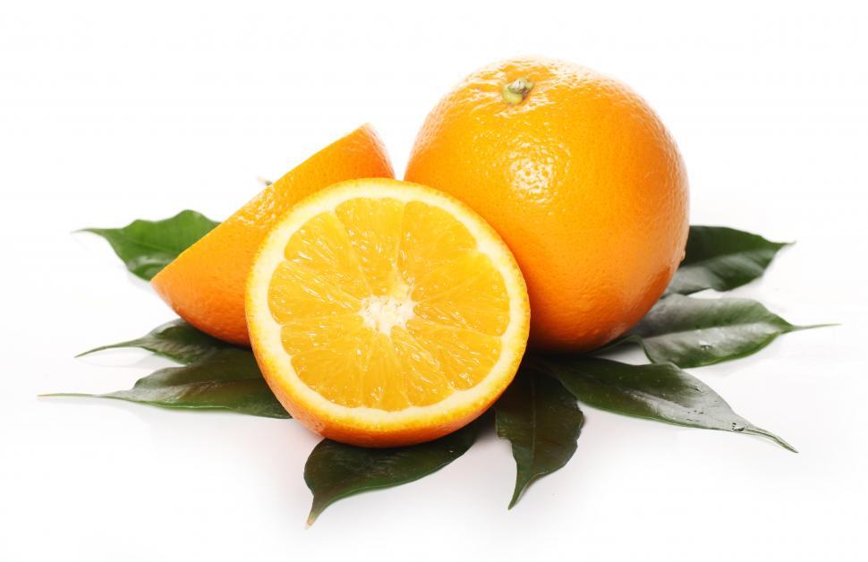 Free Image of Fresh whole and sliced oranges on bead of leaves 
