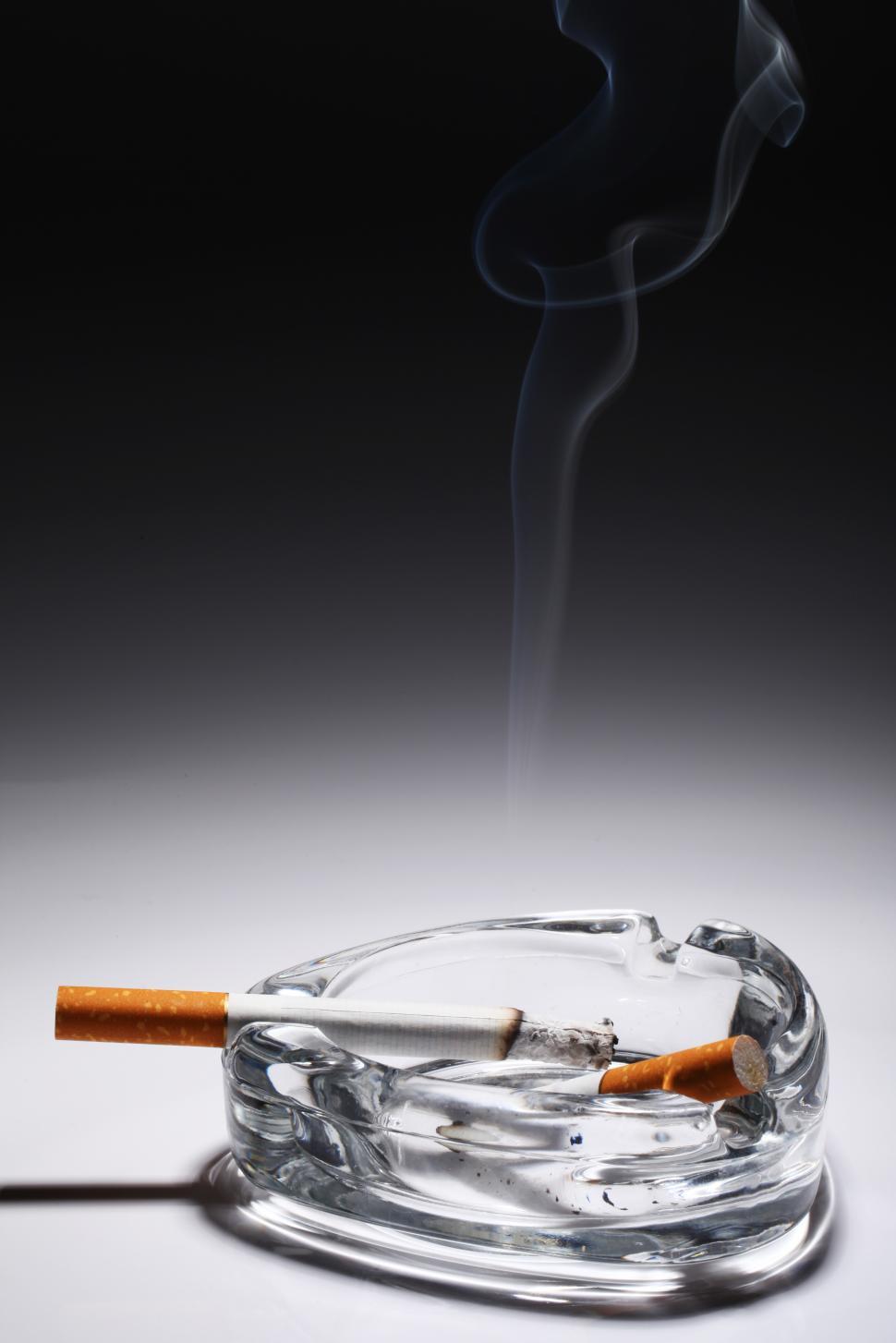 Free Image of Cigarette smolders in the glass ashtray 