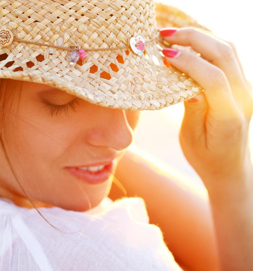 Free Image of Young woman wearing a straw hat in sunset light 
