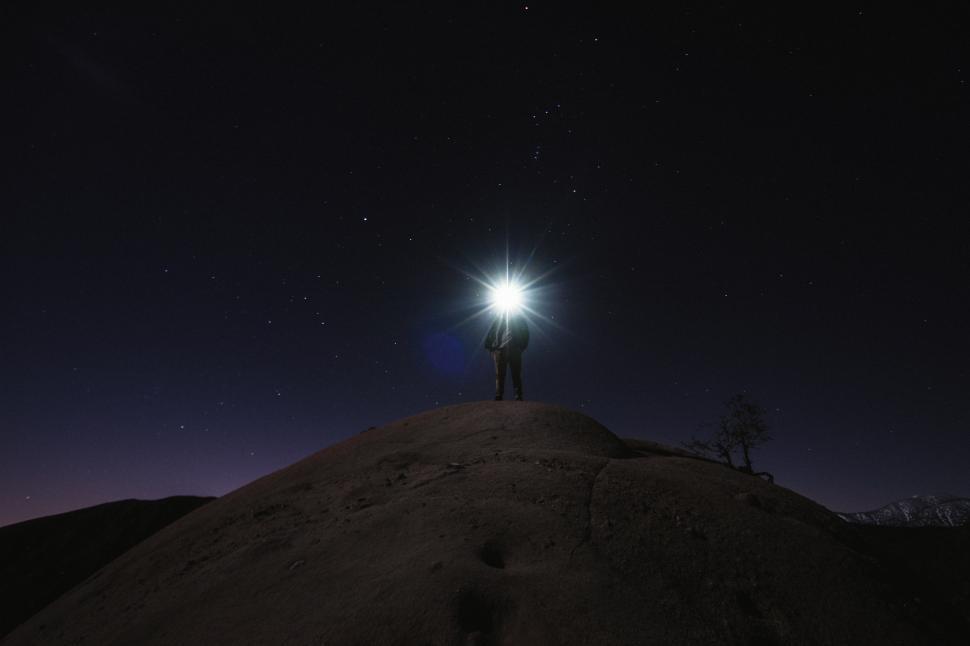 Free Image of Person with flashlight on mountain with starry sky 