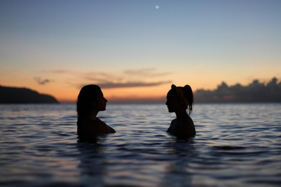 Free Image of Two women in ocean with sunset sky 
