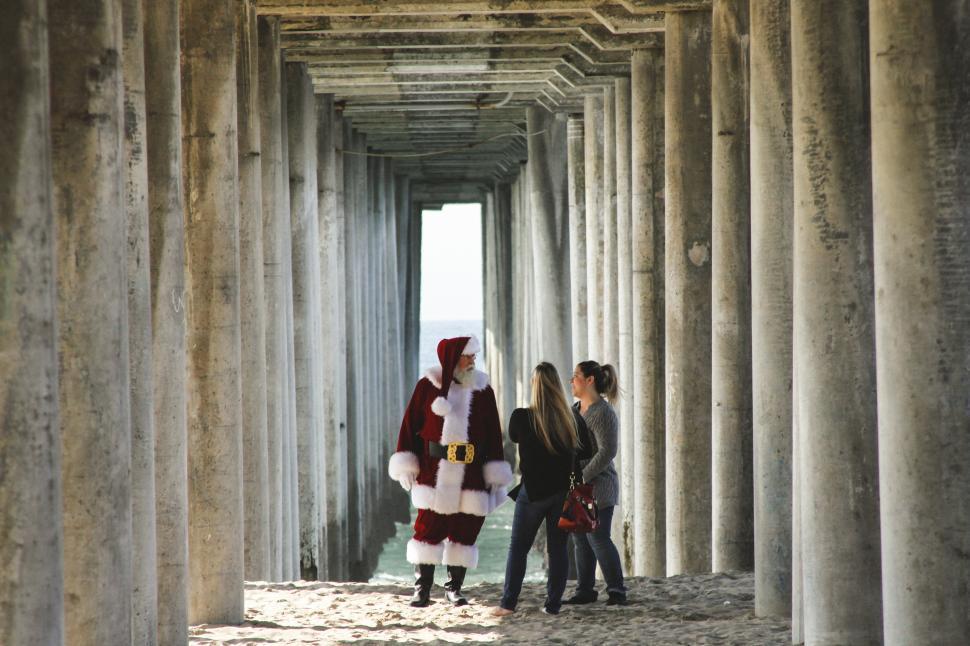 Free Image of Santa Claus and women standing under the pier 