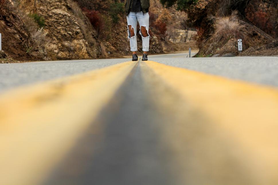 Free Image of Person standing on road surrounded by mountains 