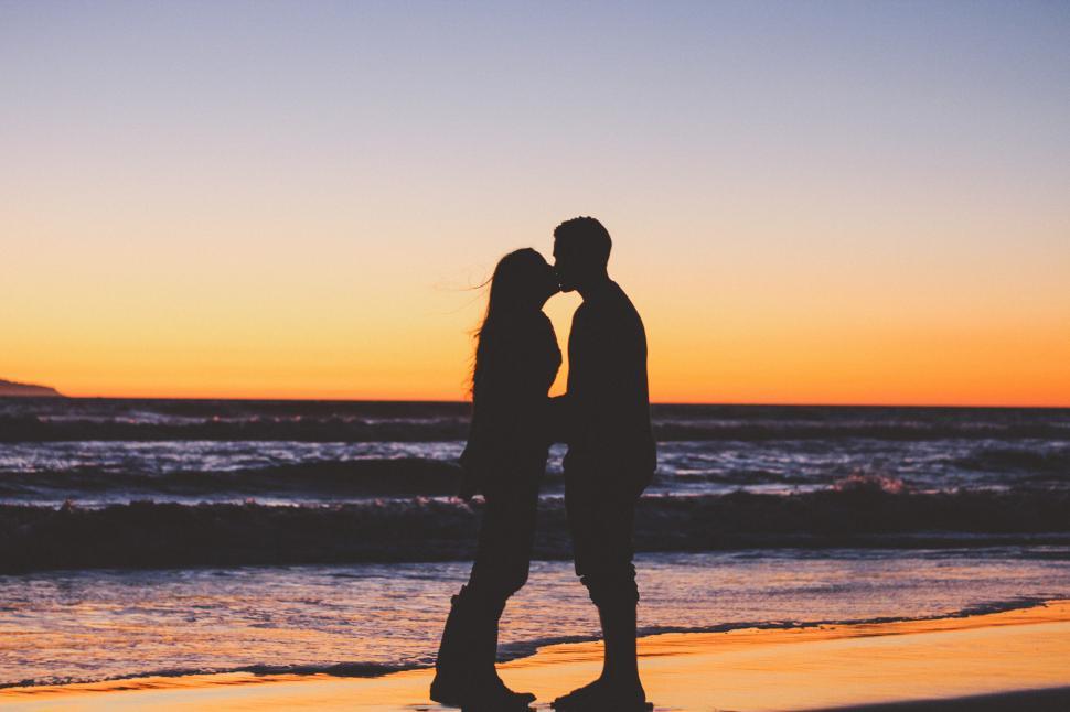 Free Image of Couple kissing at the beach during sunset 