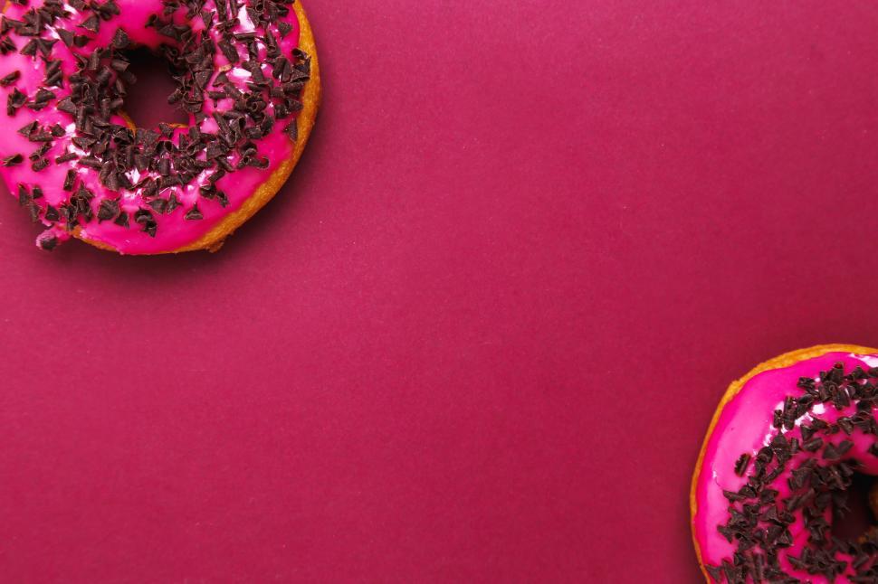 Free Image of Two pink frosted donuts on pink and red background 