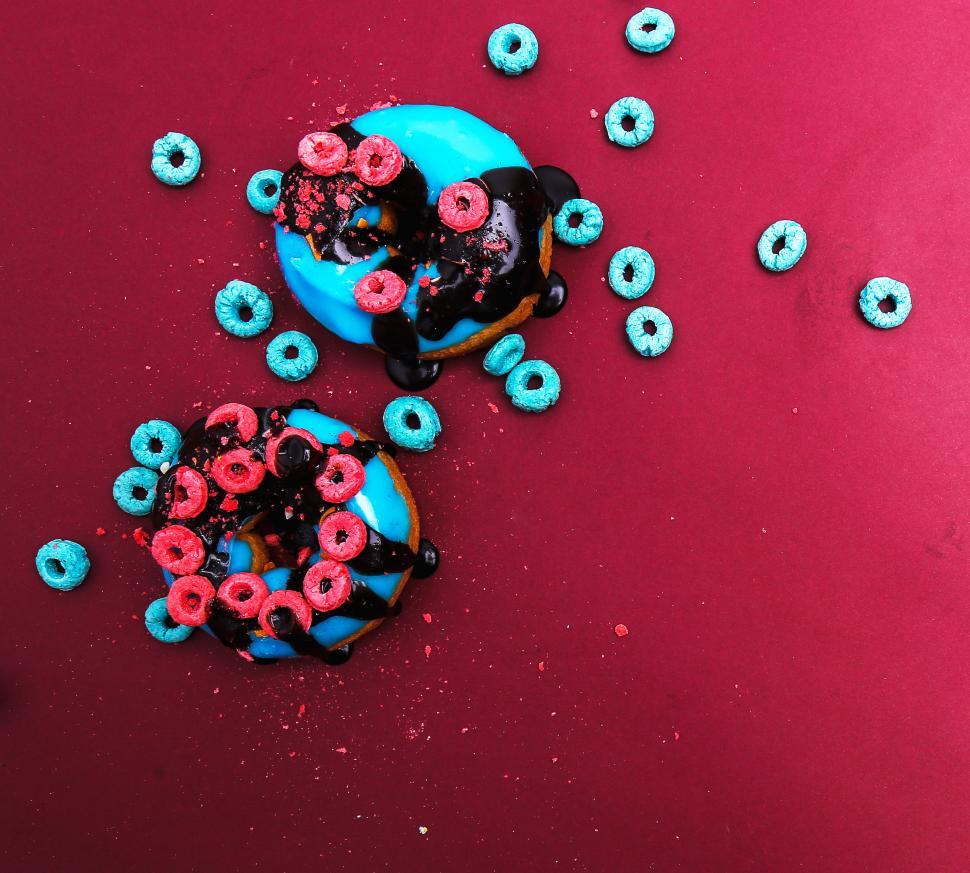 Free Image of Donuts topped with fruit loop cereal on colored background 