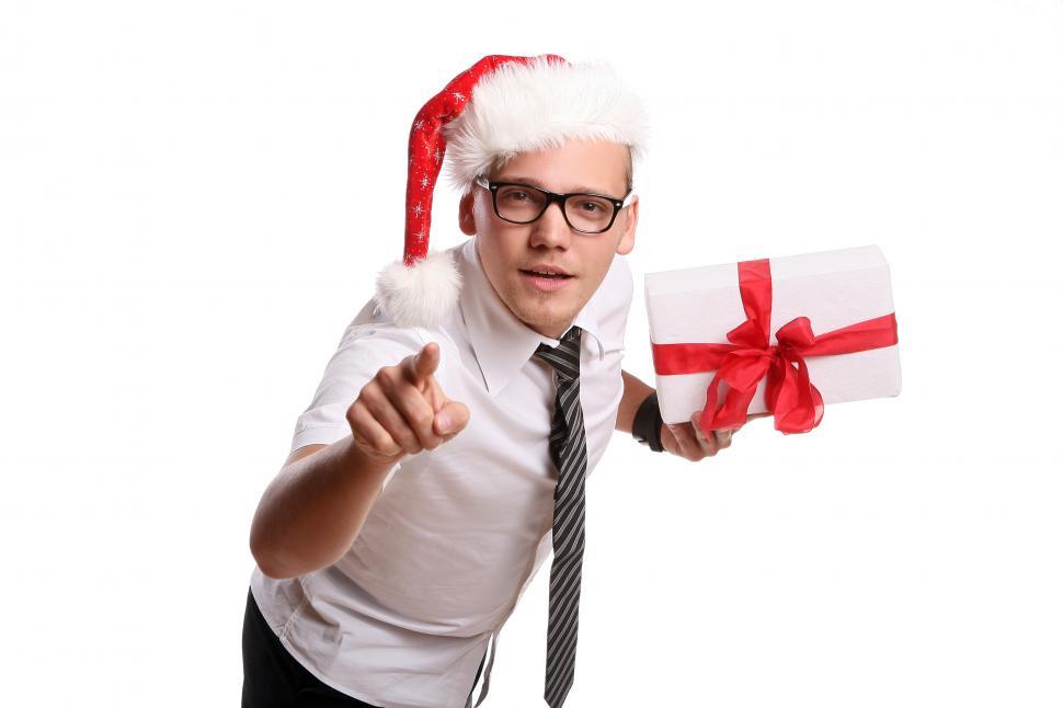 Free Image of Young office with Santa hat and gift, pointing 