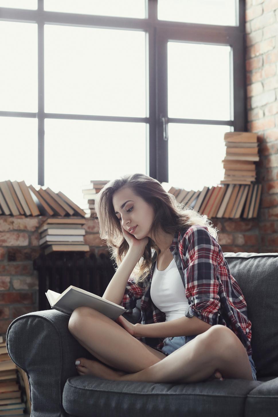 Free Image of Young woman reading, surrounded by bound books 
