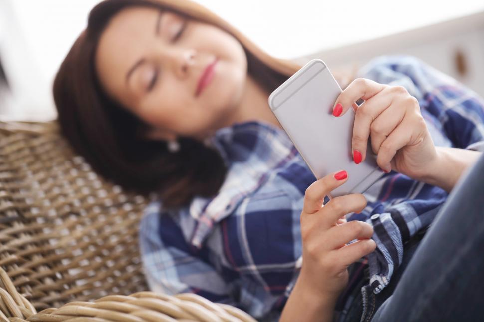 Free Image of Woman lounging while browsing on phone 