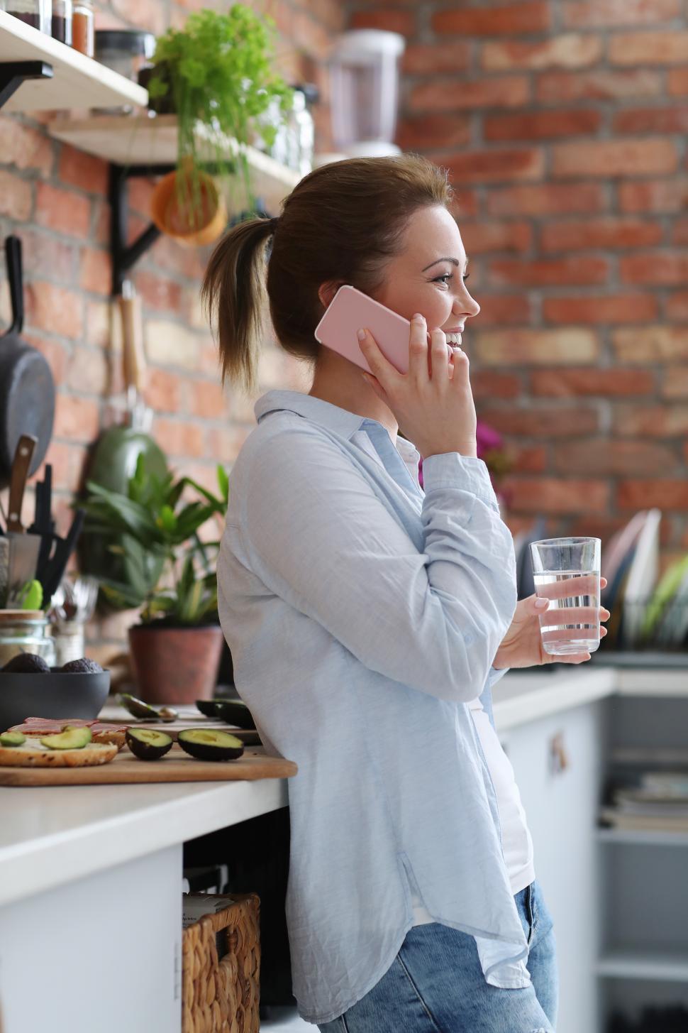 Free Image of Woman in kitchen on her phone 