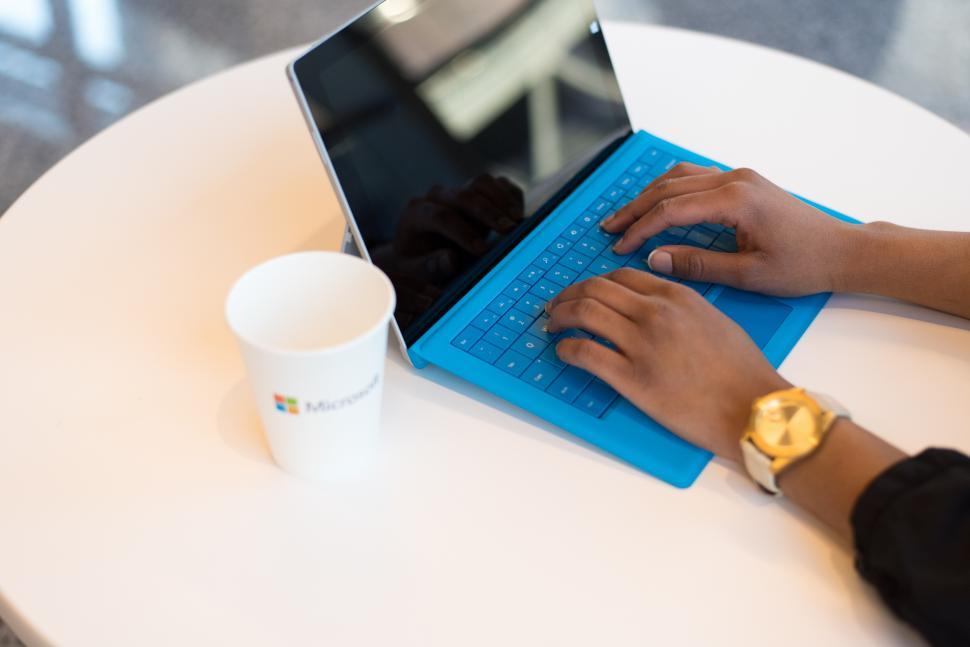 Free Image of Hands typing on blue laptop 