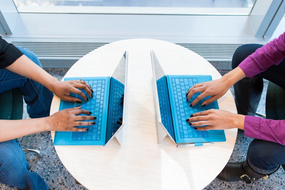 Free Image of Female co-workers hands on blue laptops 