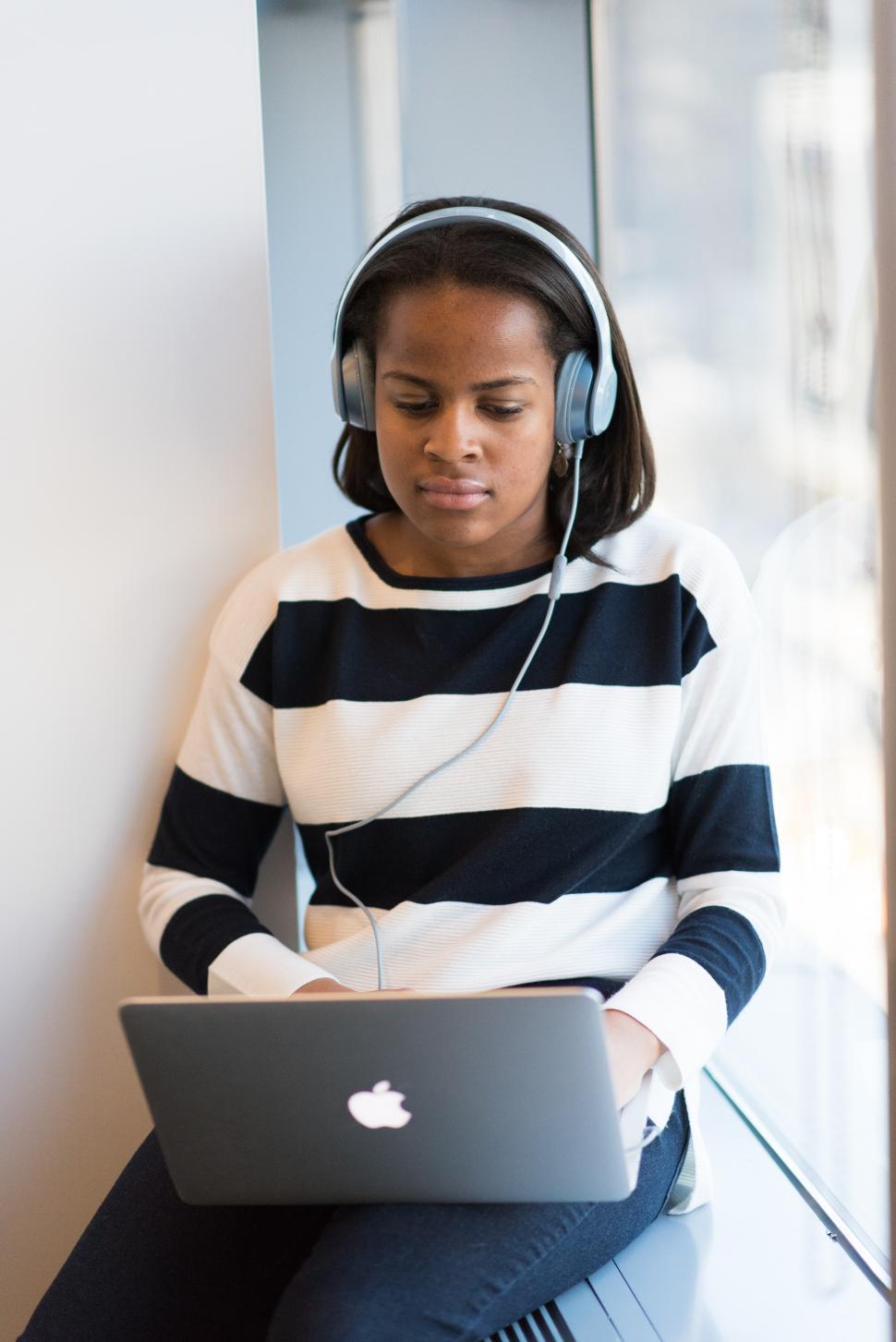 Free Image of Female using laptop with headphones - looking down 