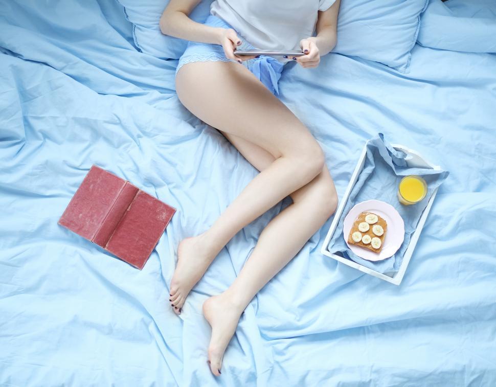 Free Image of Woman in bed with breakfast and reading materials 