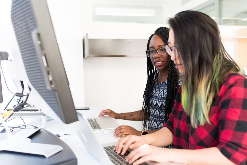 Free Image of Two Multiethnic female co-workers using laptop in office 
