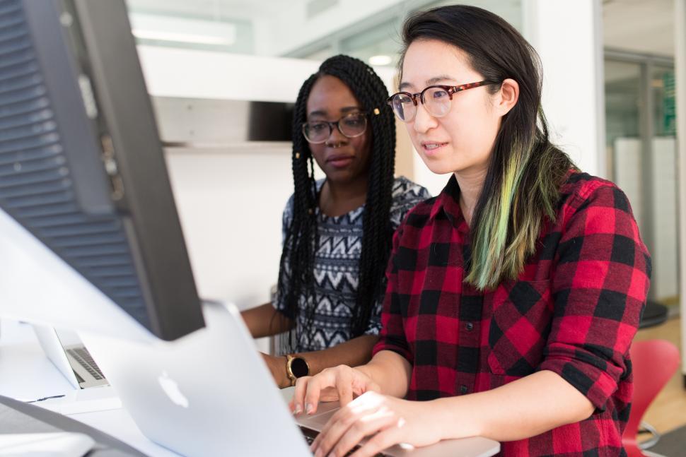 Free Image of Multiethnic female co-workers standing and using laptop in offic 