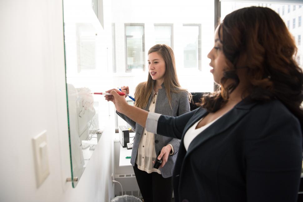 Free Image of Two business women with marker pen and whiteboard 