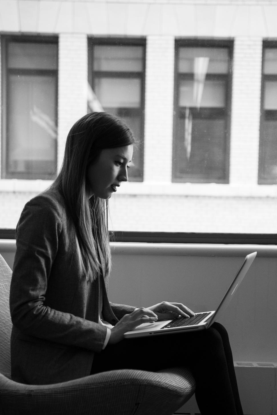 Free Image of Female using laptop near window in office - b&w 