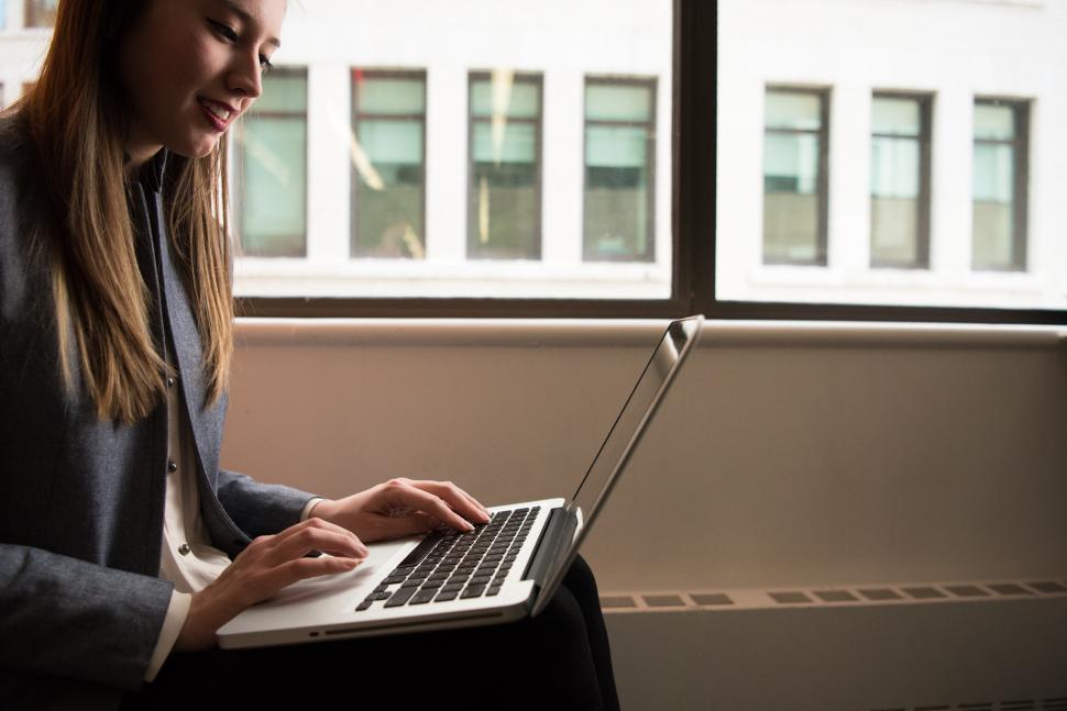 Free Image of Happy Woman typing on laptop - looking down 